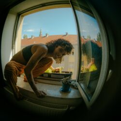 Das Foto zeigt die Künstlerin Vandalisbin auf einer Fensterbank sitzend.